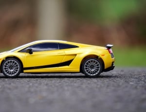 yellow coupe diecast on grey concrete road thumbnail