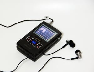 black MP3 player with earbuds on white surface thumbnail