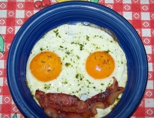 two sunny side up eggs and bacon strip thumbnail