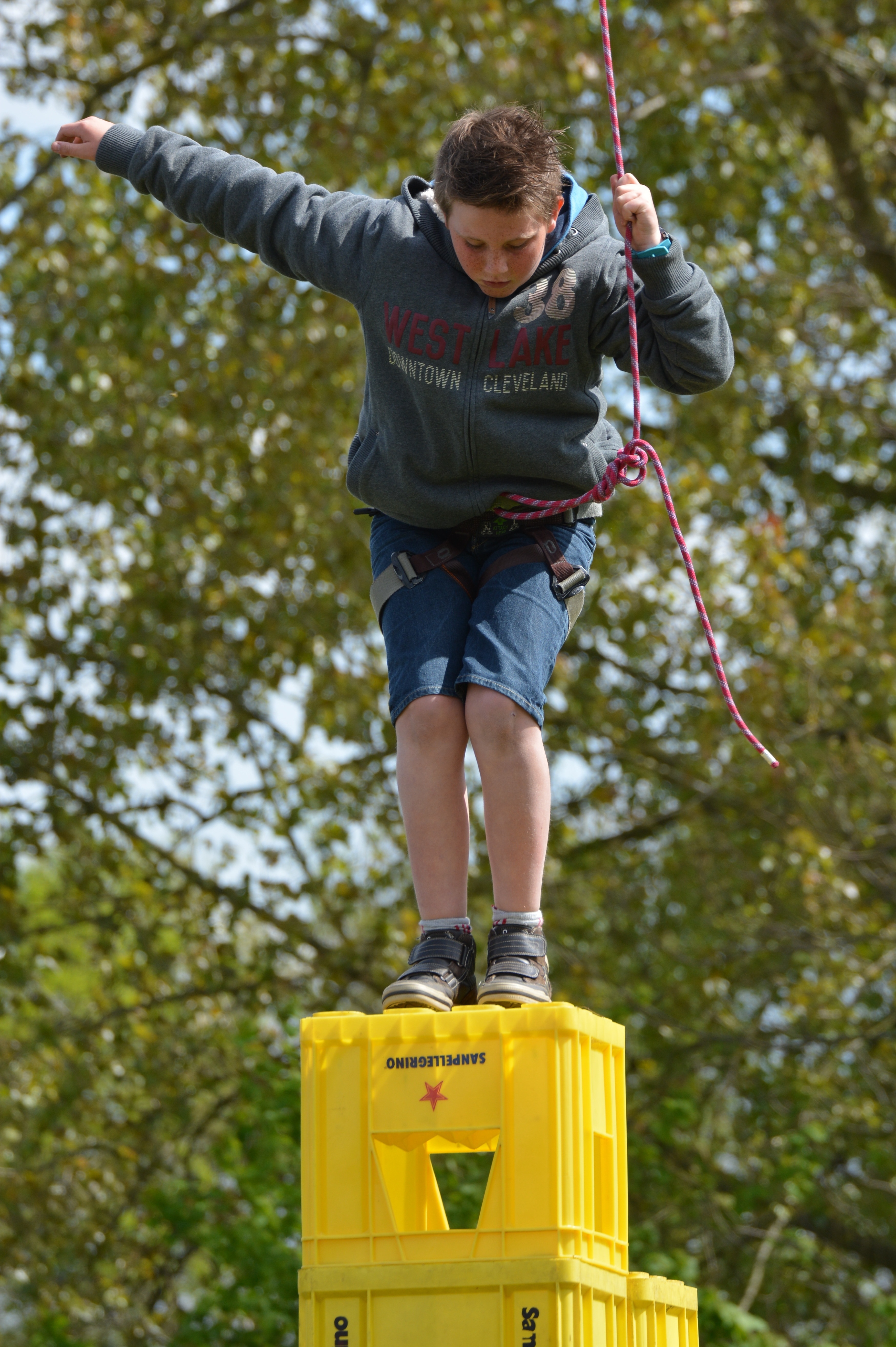 boy wearing hooded jacket on top of plastic crate