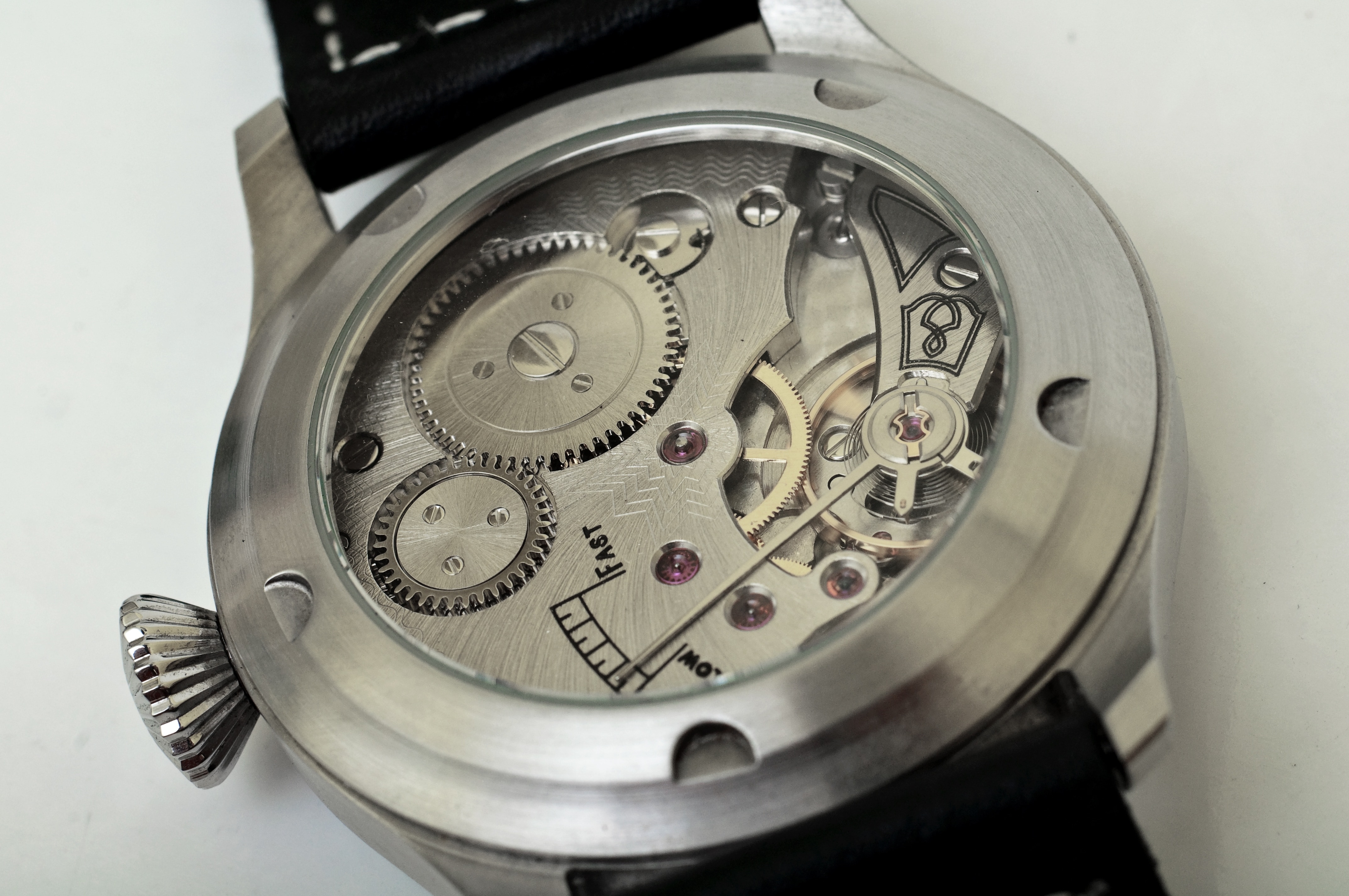close-up of round silver mechanical watch on black surface