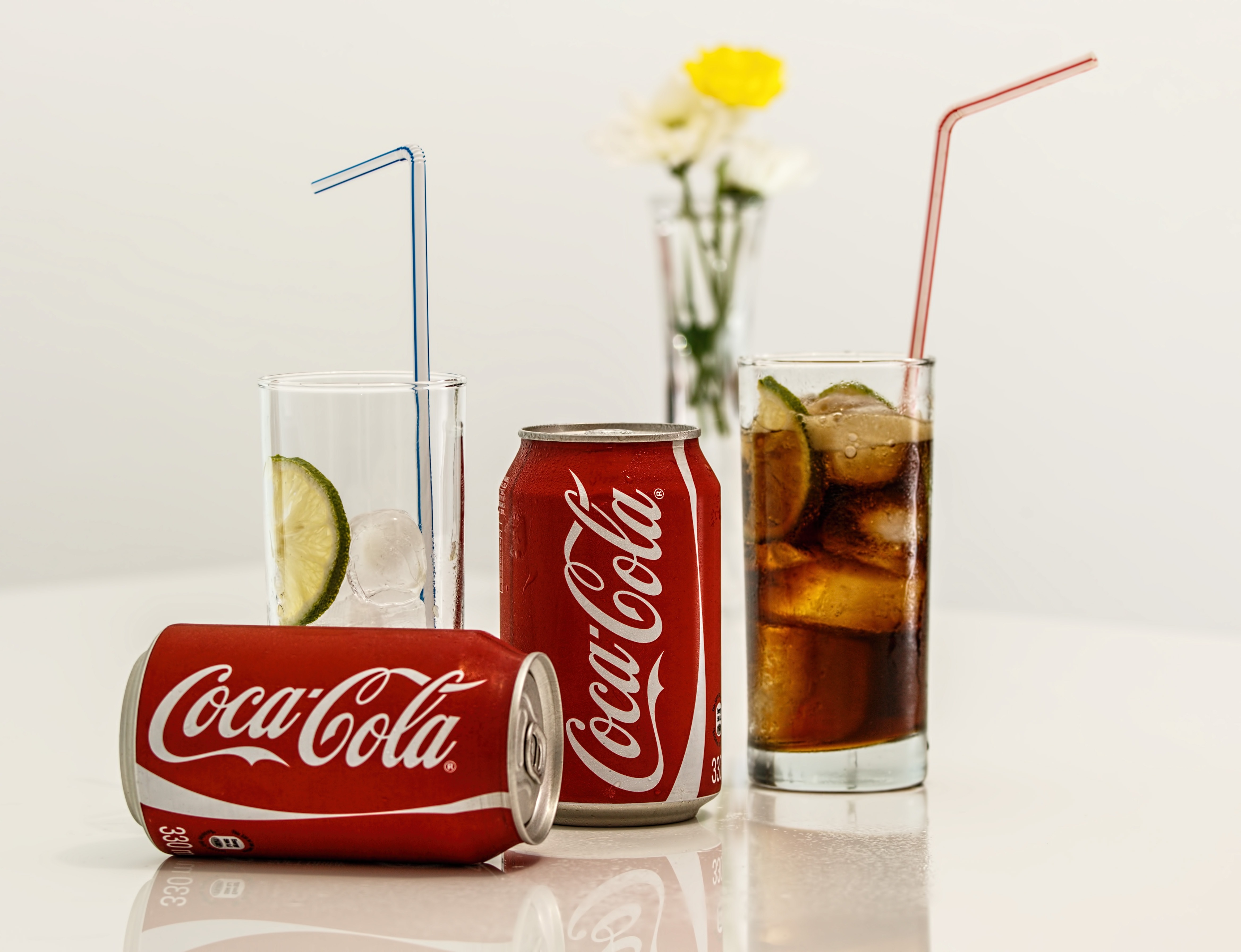 two Coca-Cola cans with two drinking glasses
