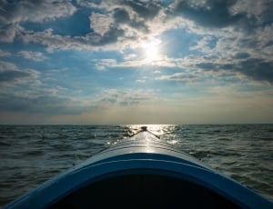 blue boat on ocean under blue skies and white clouds thumbnail