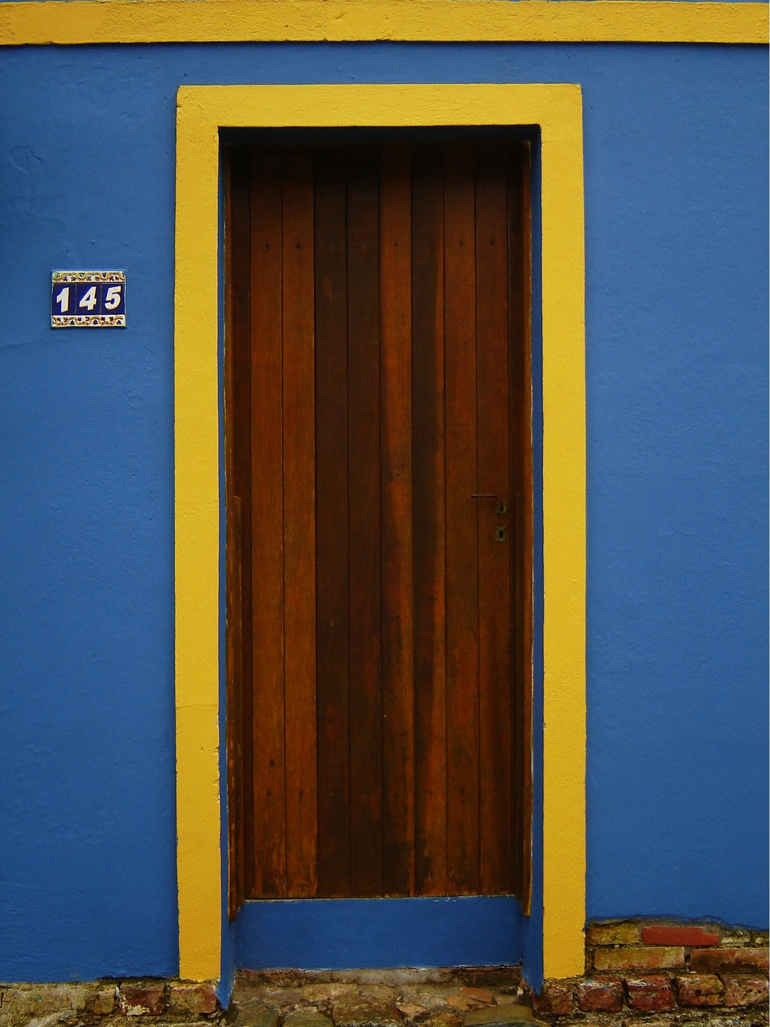 blue and yellow facade with brown wooden door