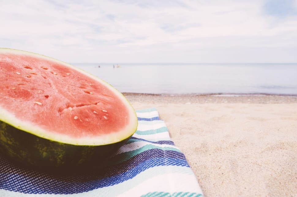 low angle photography of slice of melon on textile in beach on daytime preview
