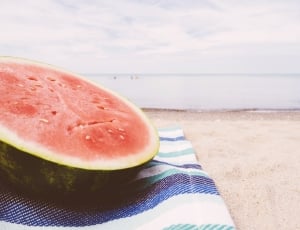 low angle photography of slice of melon on textile in beach on daytime thumbnail