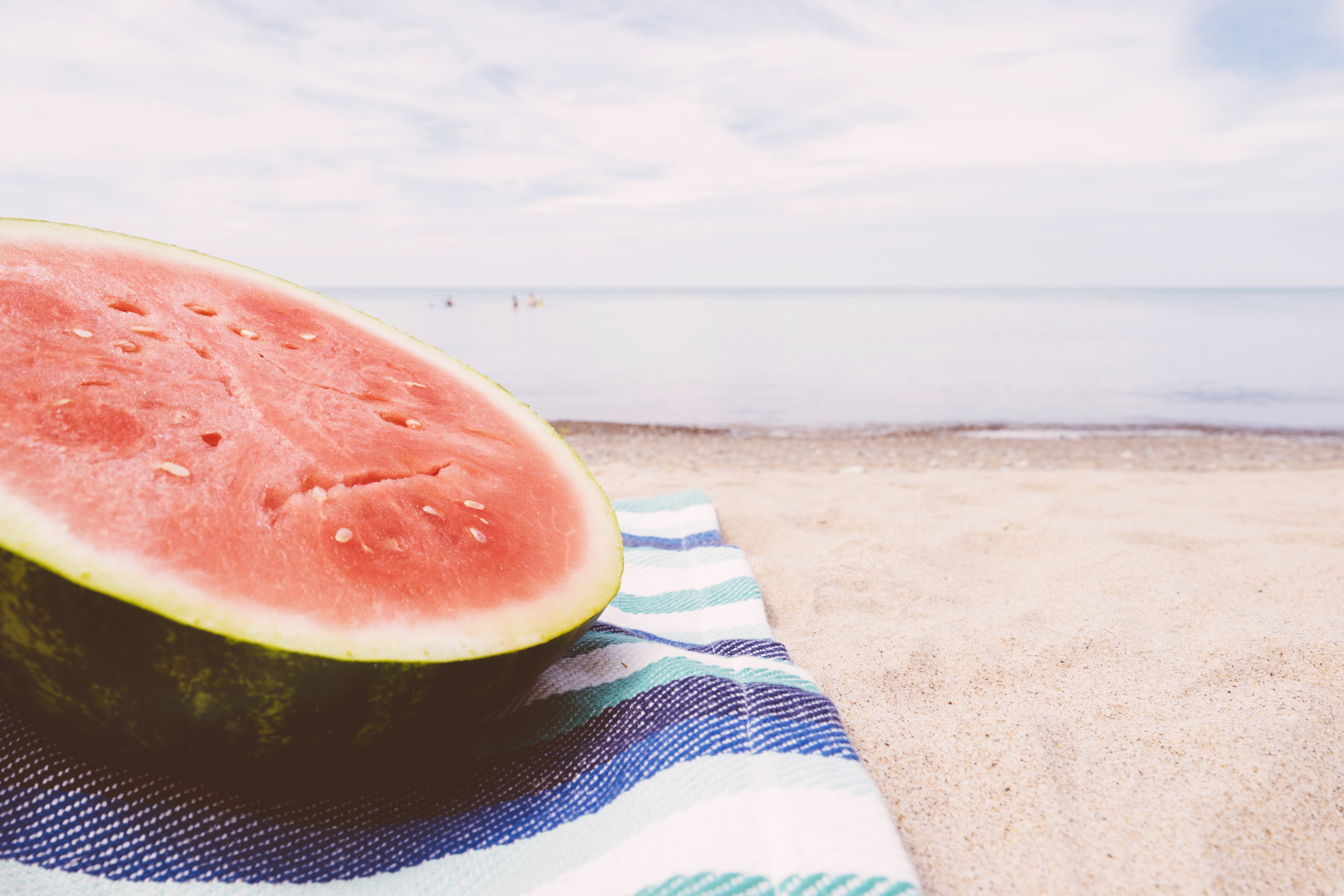 low angle photography of slice of melon on textile in beach on daytime