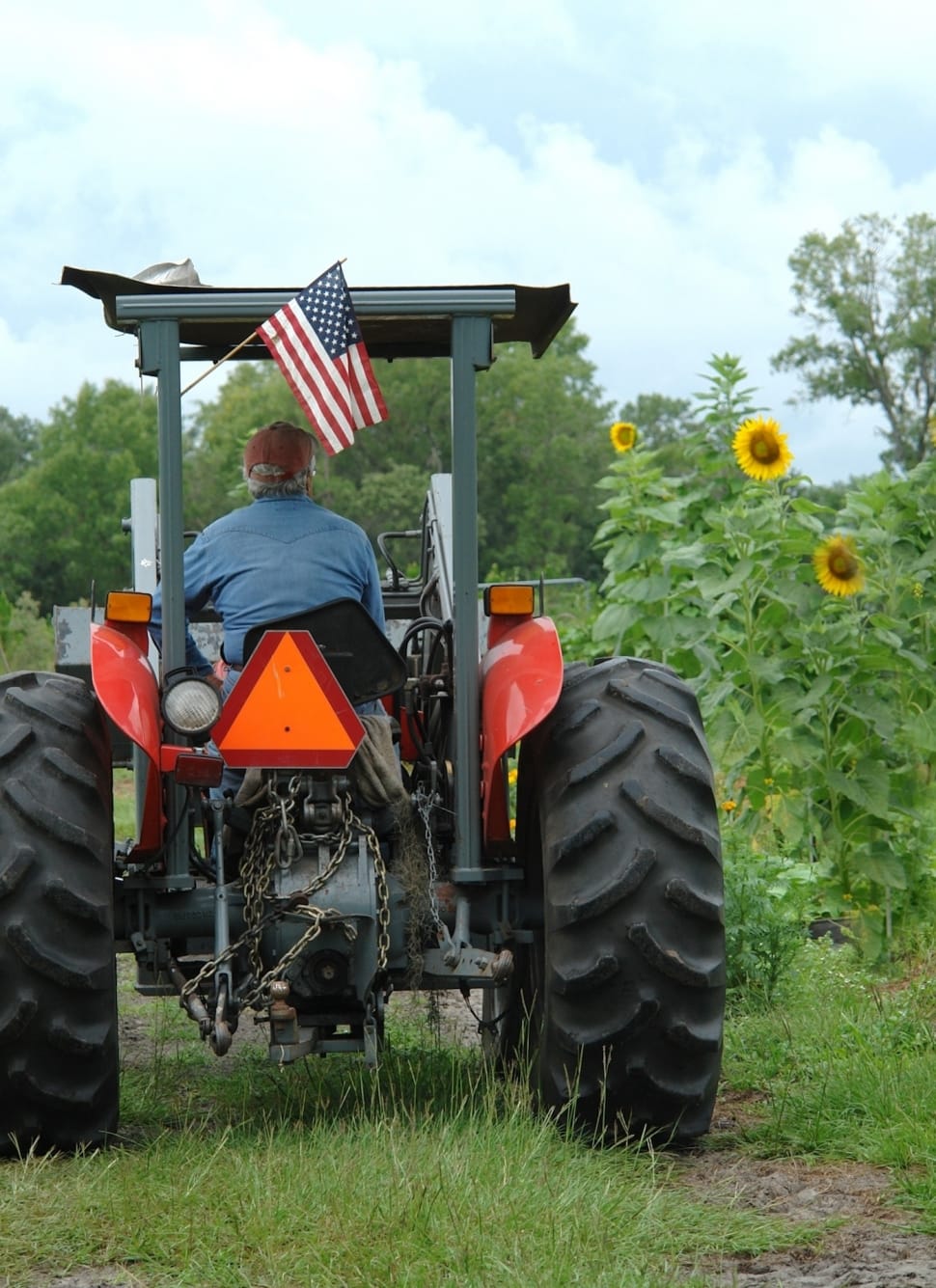 man in blue long sleeves driving farm tractor during day time preview