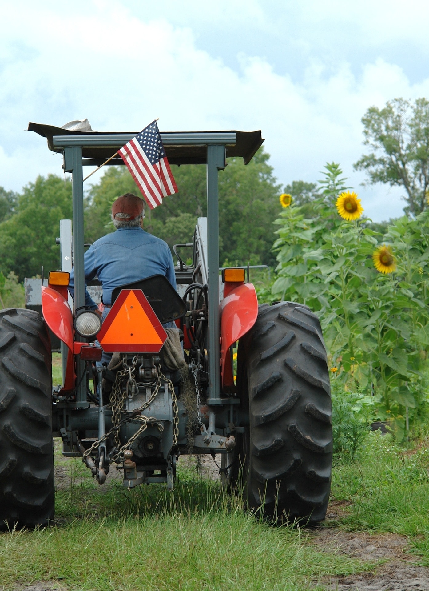 man in blue long sleeves driving farm tractor during day time