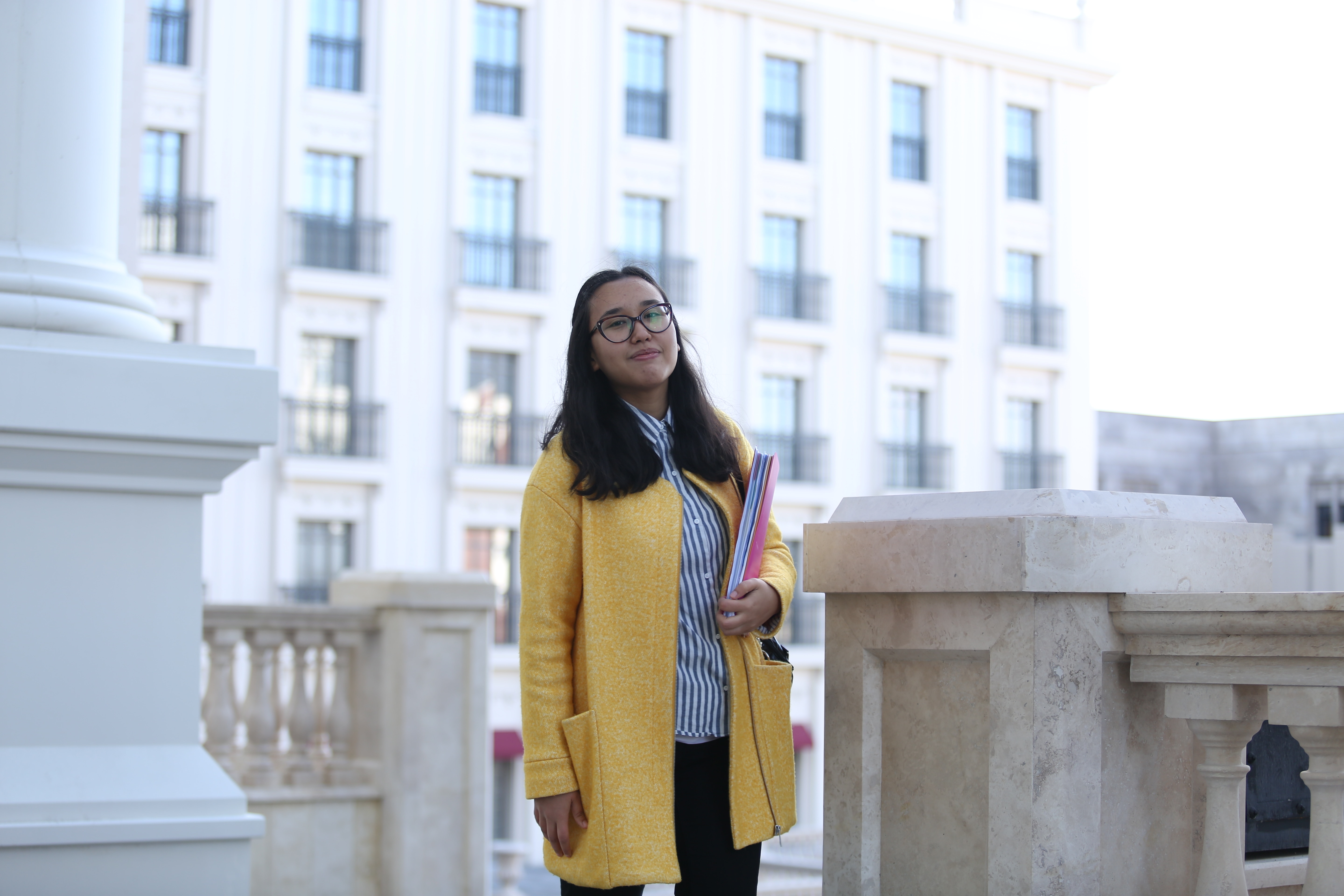 woman in white and black stripe shirt, black pants and yellow cardigan