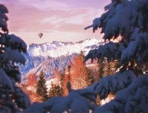 white hot air balloon flying over snowy mountains thumbnail