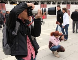 man taking picture using DSLR camera with extended lens thumbnail
