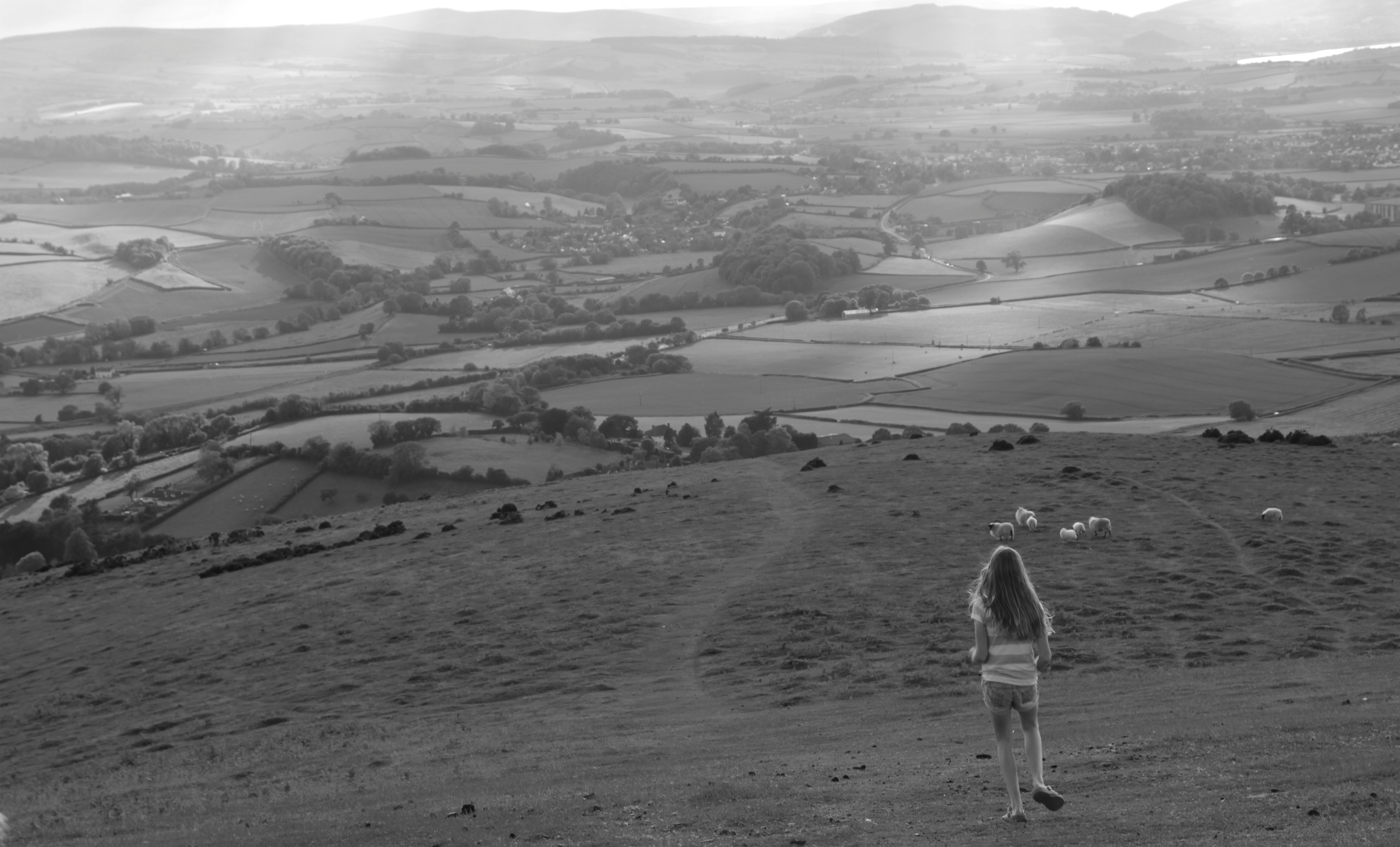 grayscale photo of girl walking on hills