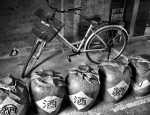 grayscale photo of commuter bike near five terracotta floor vases thumbnail