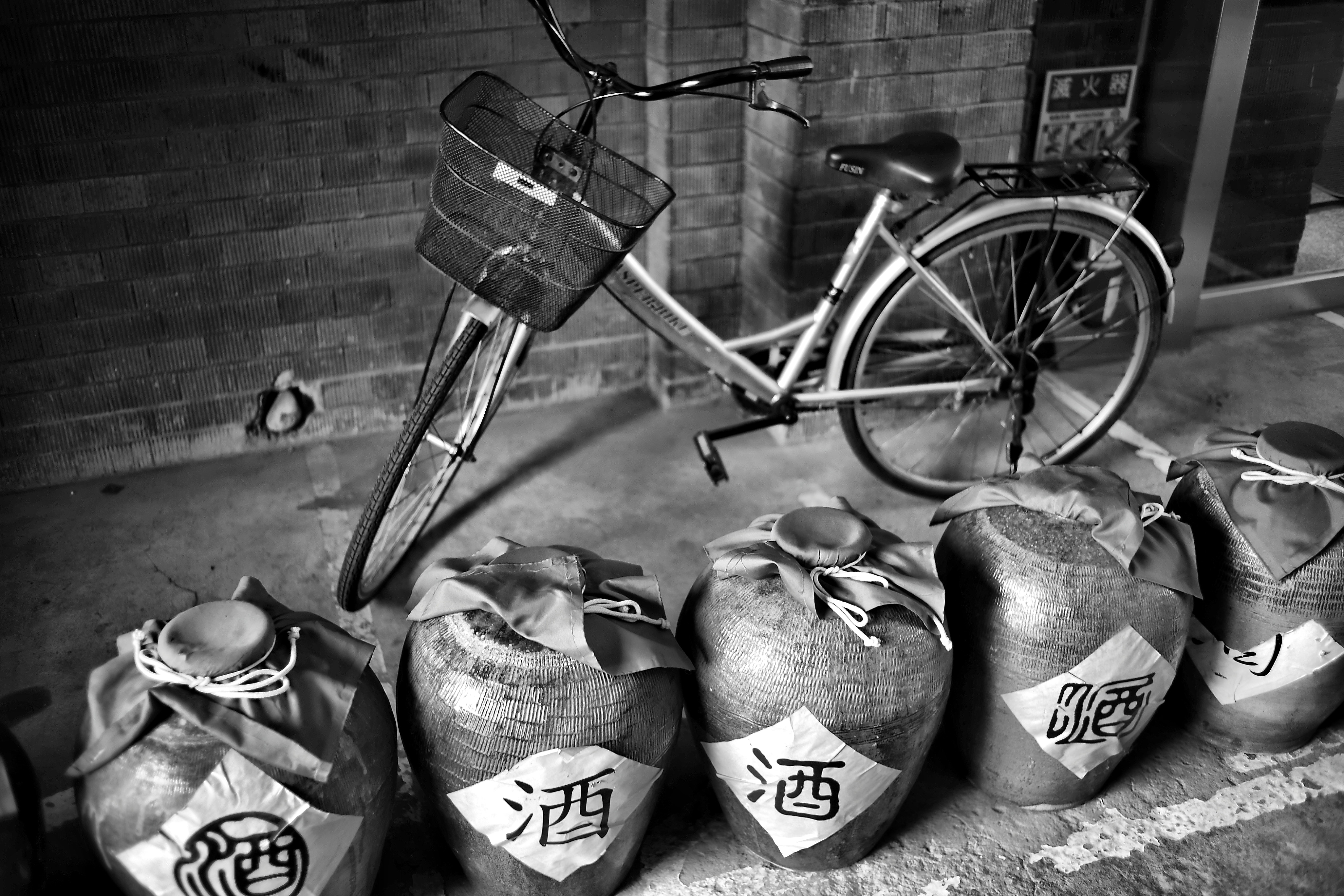 grayscale photo of commuter bike near five terracotta floor vases