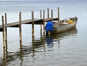 grey motor boat beside a brown wooden dock during daytime thumbnail