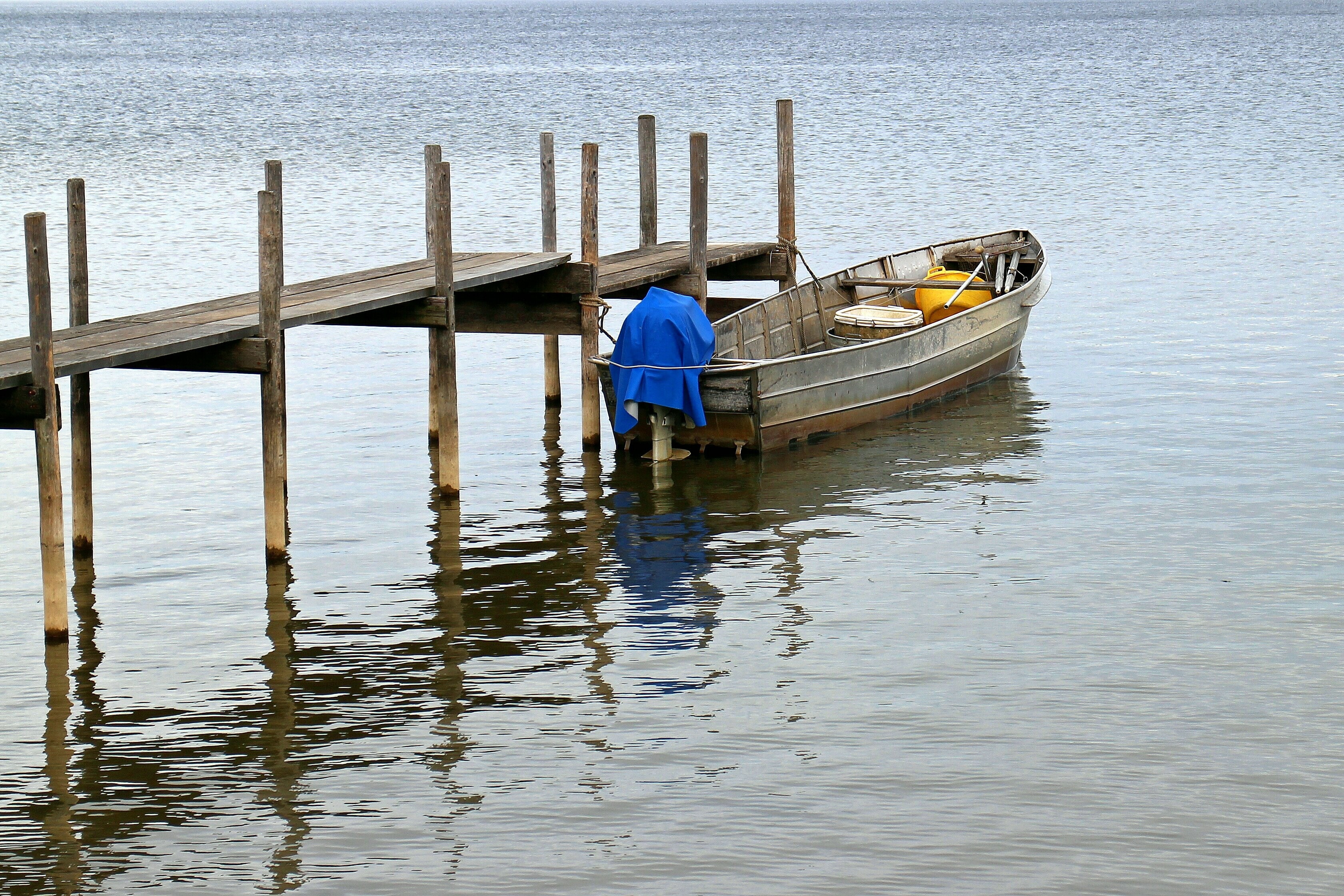 grey motor boat beside a brown wooden dock during daytime