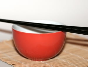 red ceramic bowl and 2 black chopsticks thumbnail