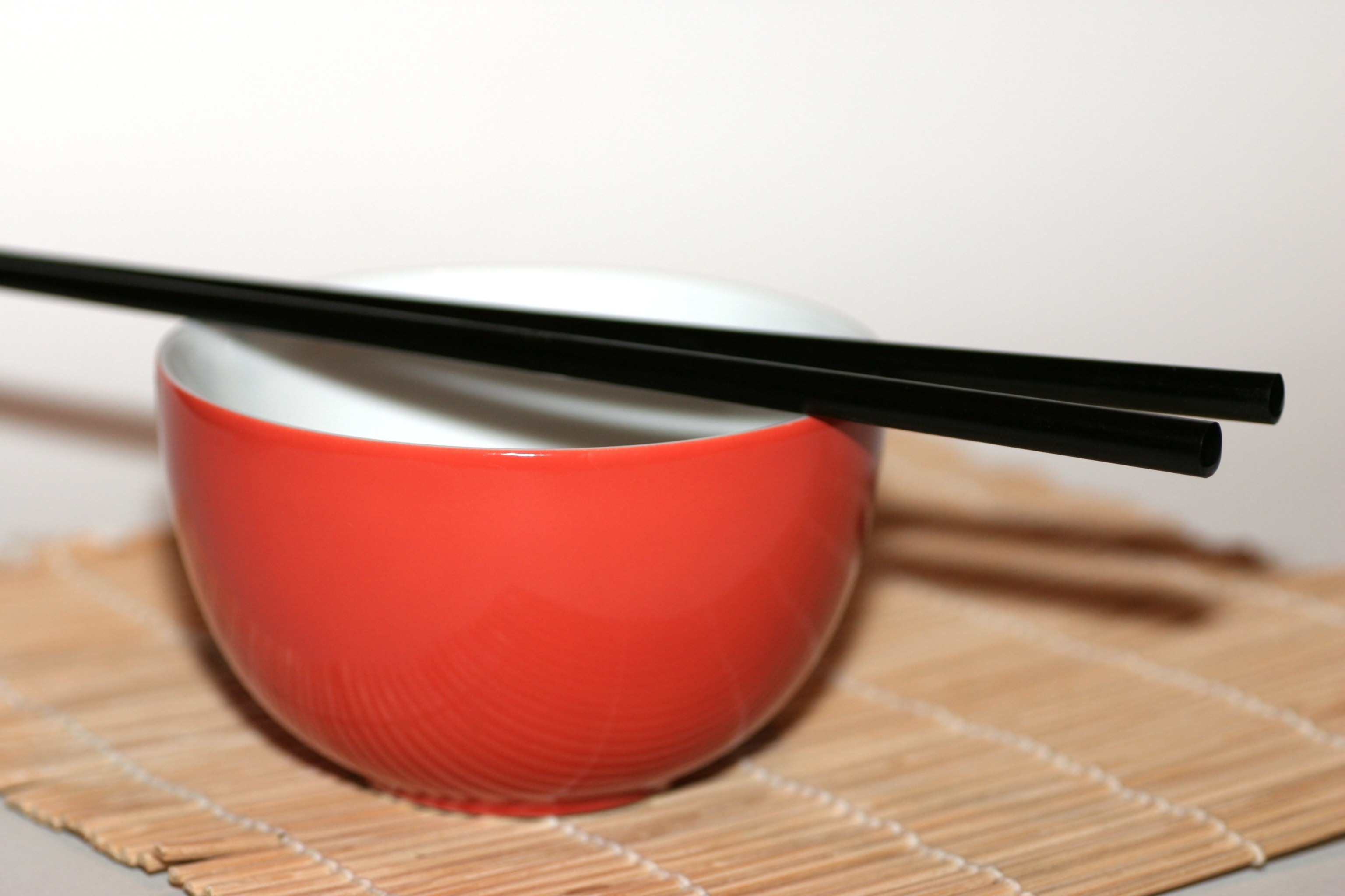 red ceramic bowl and 2 black chopsticks