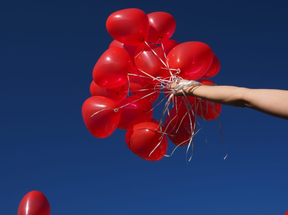 person holding red balloons preview
