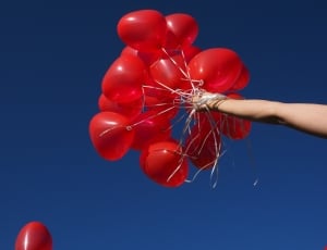 person holding red balloons thumbnail