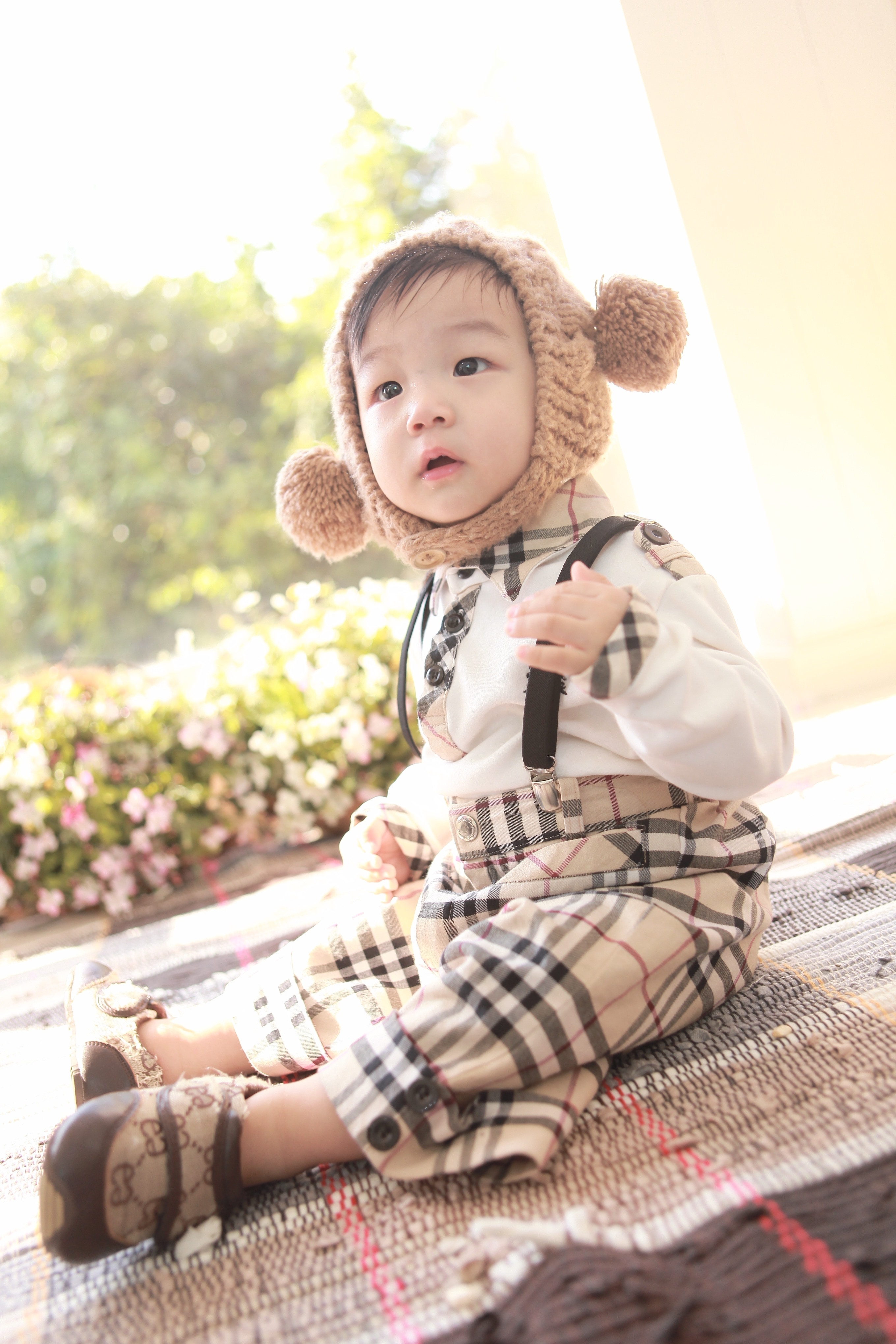 boy wearing Burberry classic overall pants and dress shirt sitting on gray mat
