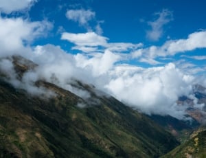 aerial view of green mountain covered with white clouds thumbnail
