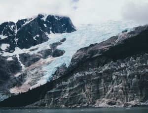 rocky glacier mountain near body of water thumbnail