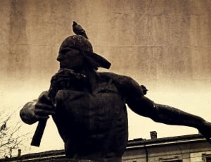 grayscale photo of man holding weapon statue thumbnail