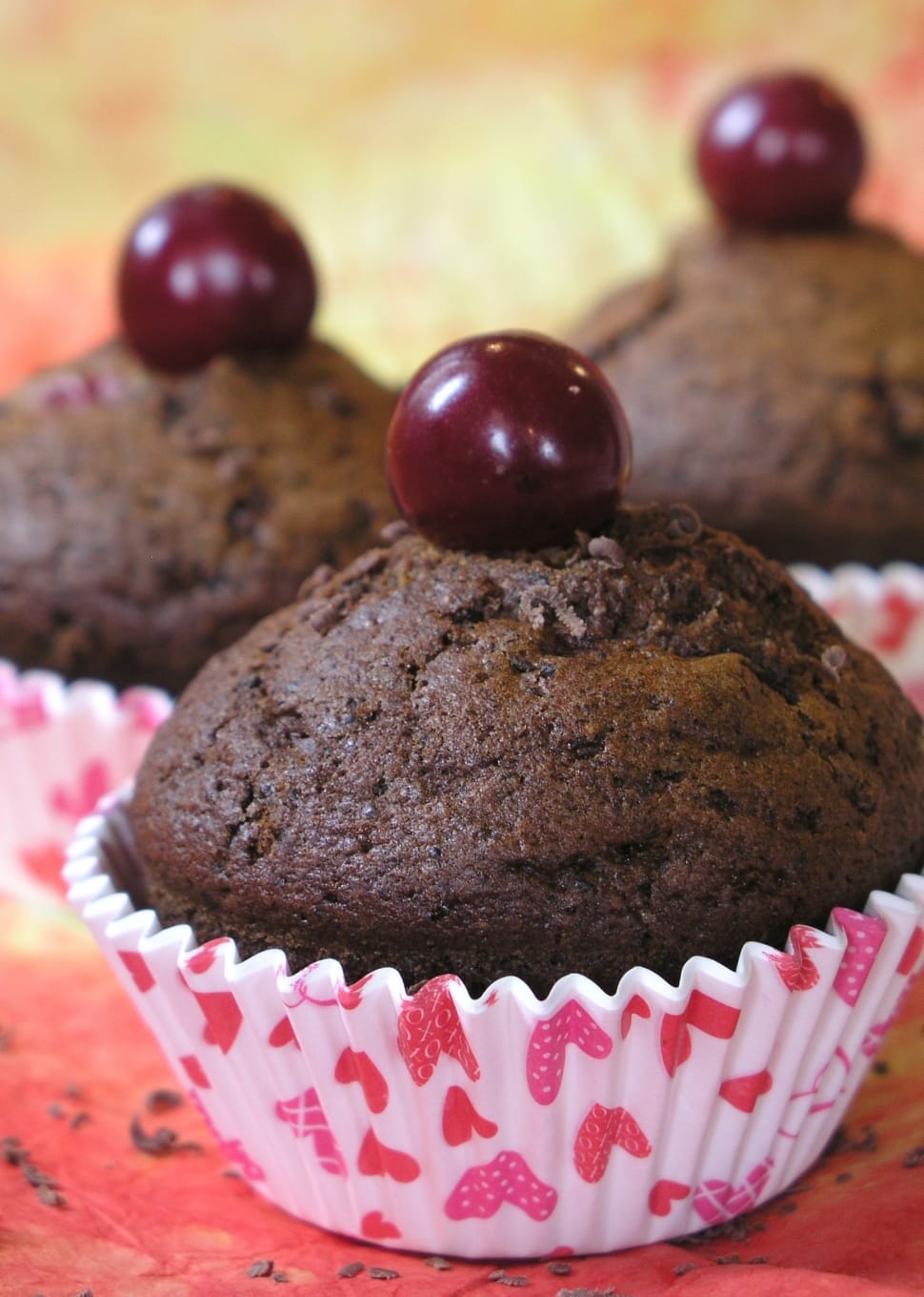 three chocolate muffins with red berry on top preview