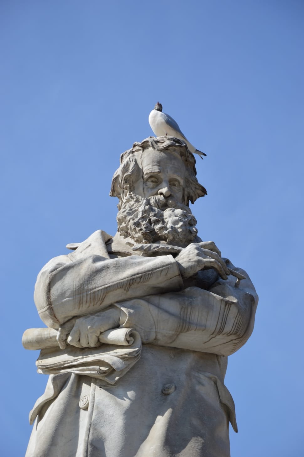 man in coat with bird on his head statue preview