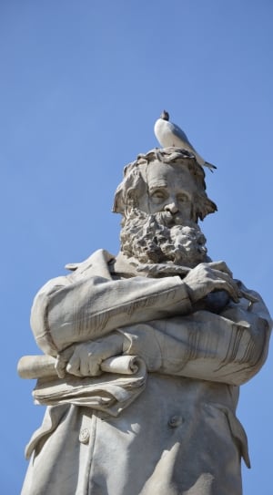 man in coat with bird on his head statue thumbnail
