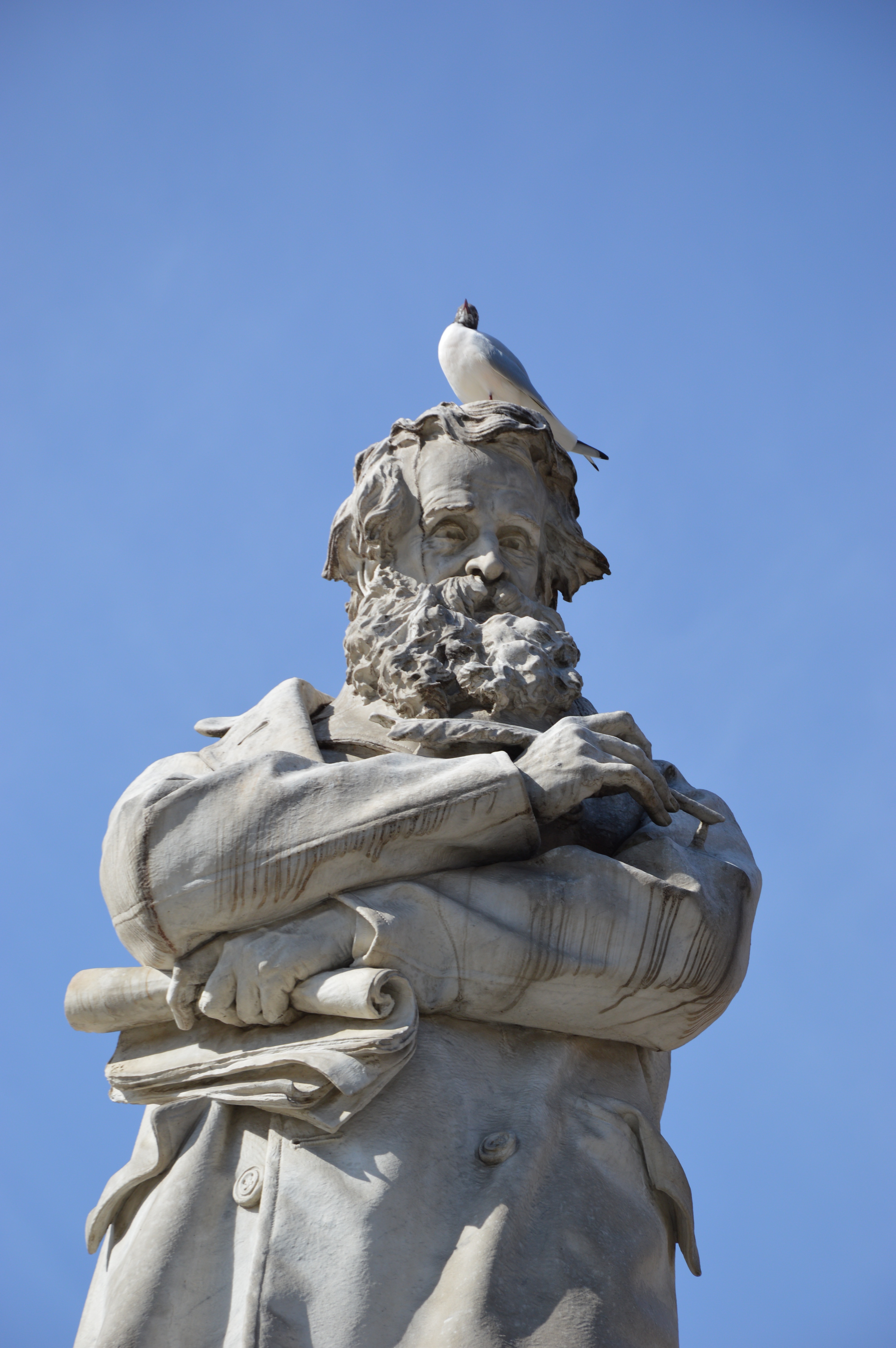 man in coat with bird on his head statue