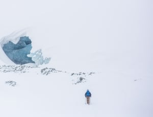 person in blue winter jacket climbing snow covered mountains thumbnail