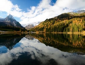 photo of body of water near mountains under blue sky thumbnail