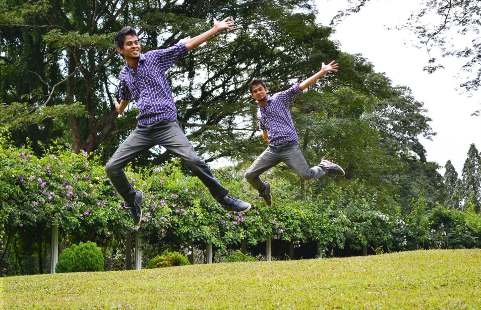 two men jumping on green open field during daytime preview