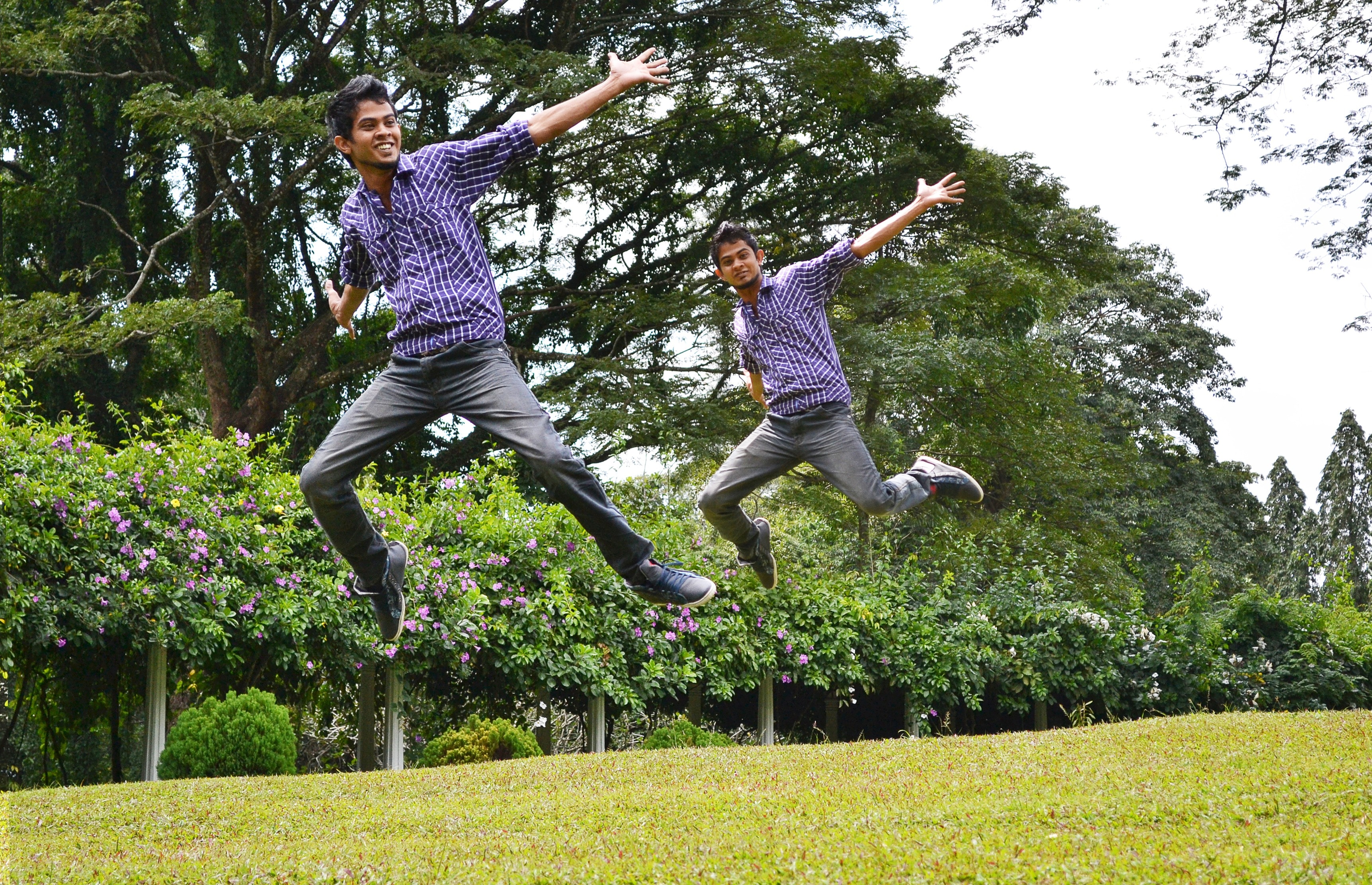 two men jumping on green open field during daytime