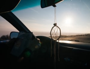 black dream catcher hanged on car rear view mirror during daytime thumbnail