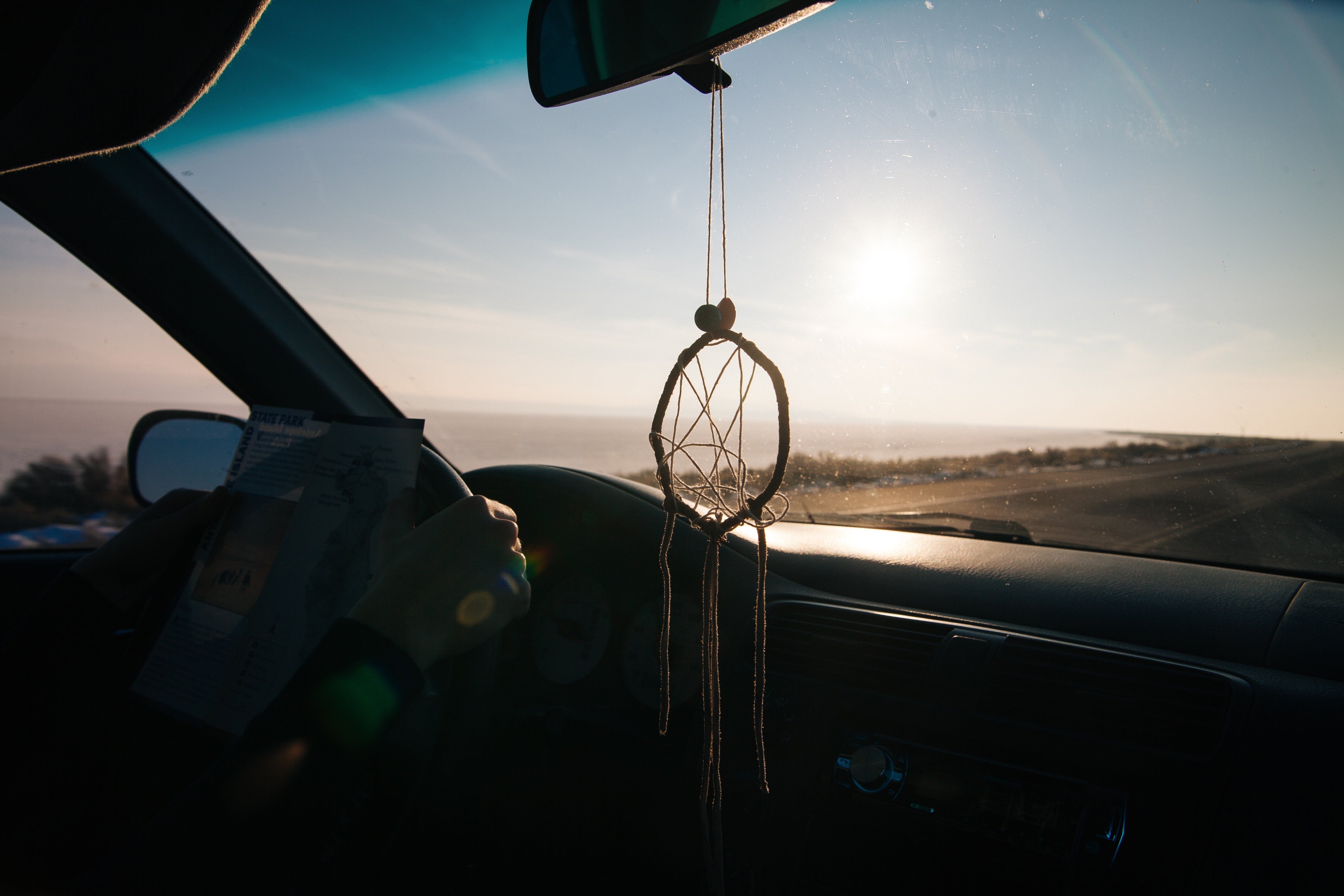 black dream catcher hanged on car rear view mirror during daytime