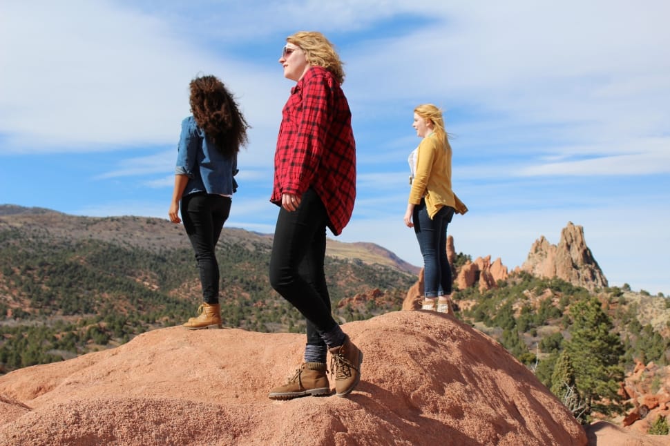 three women standing on rock under blue sky preview