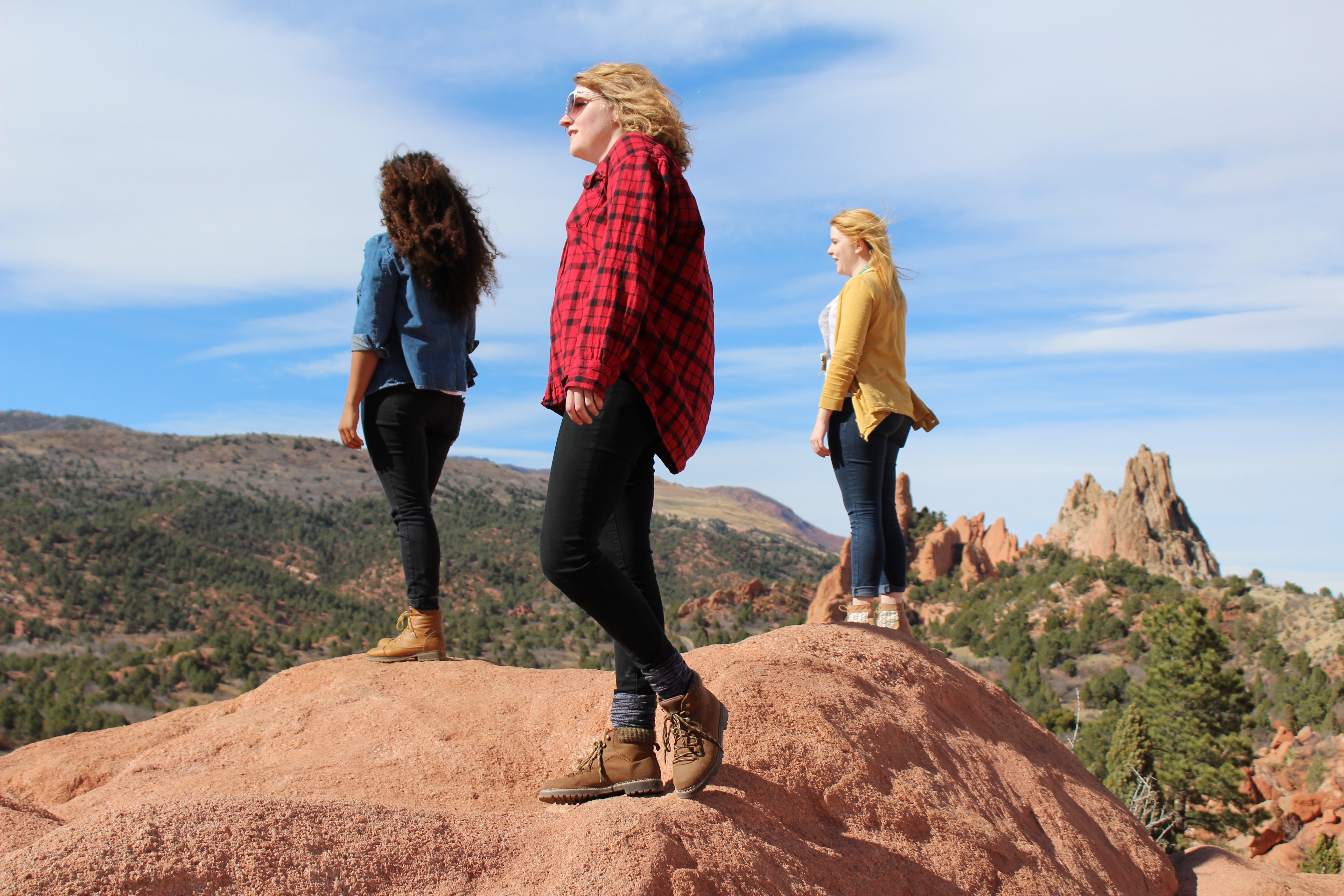 three women standing on rock under blue sky