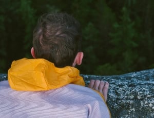 person wearing white and yellow jacket looking at trees thumbnail