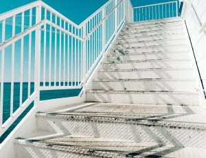 shallow focus photography of white steel staircase near blue ocean water during daytime thumbnail