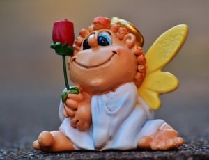 brown haired angel holding rose ceramic figurine thumbnail
