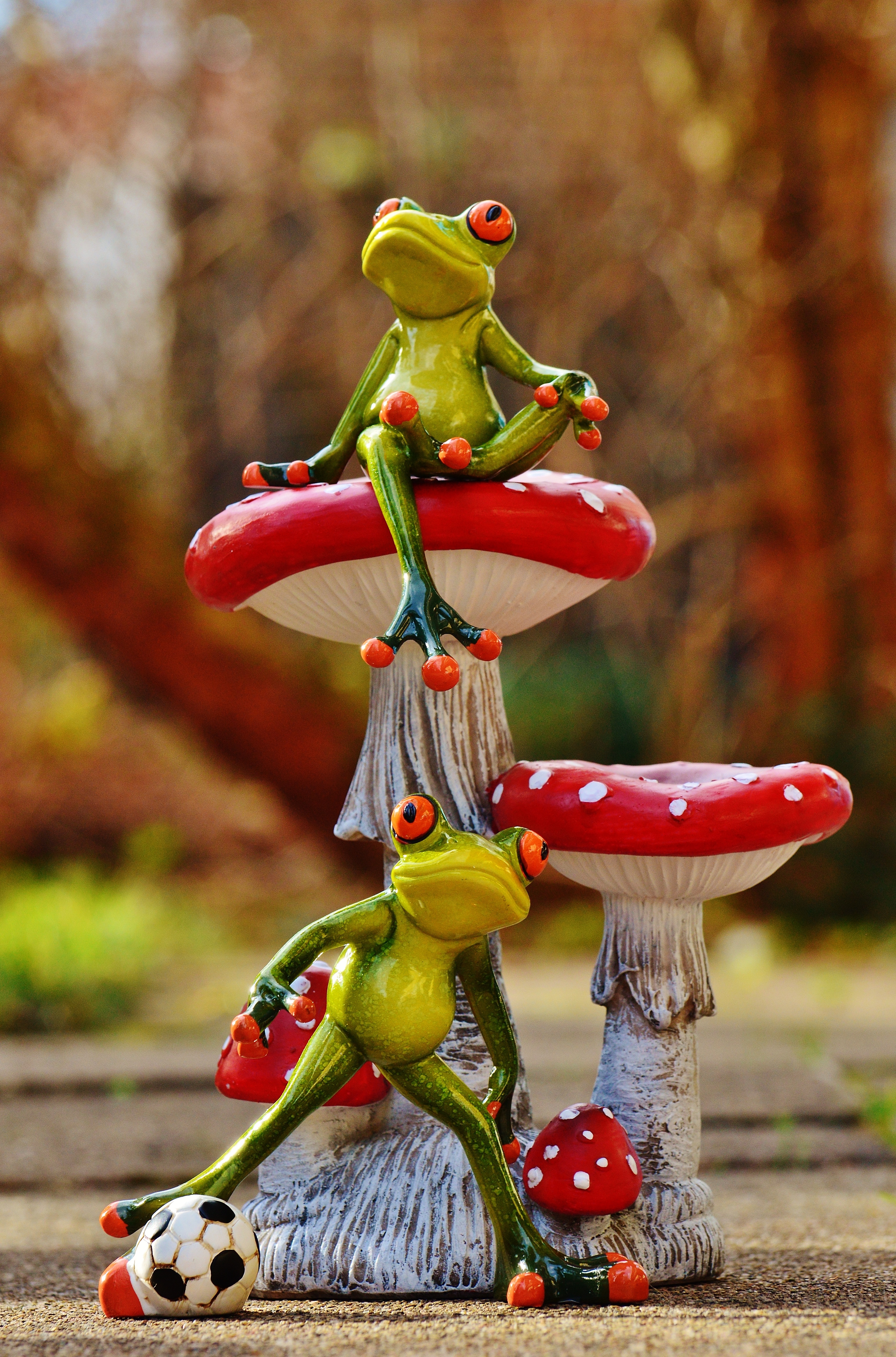 two frog on red mushroom statue in macro photography