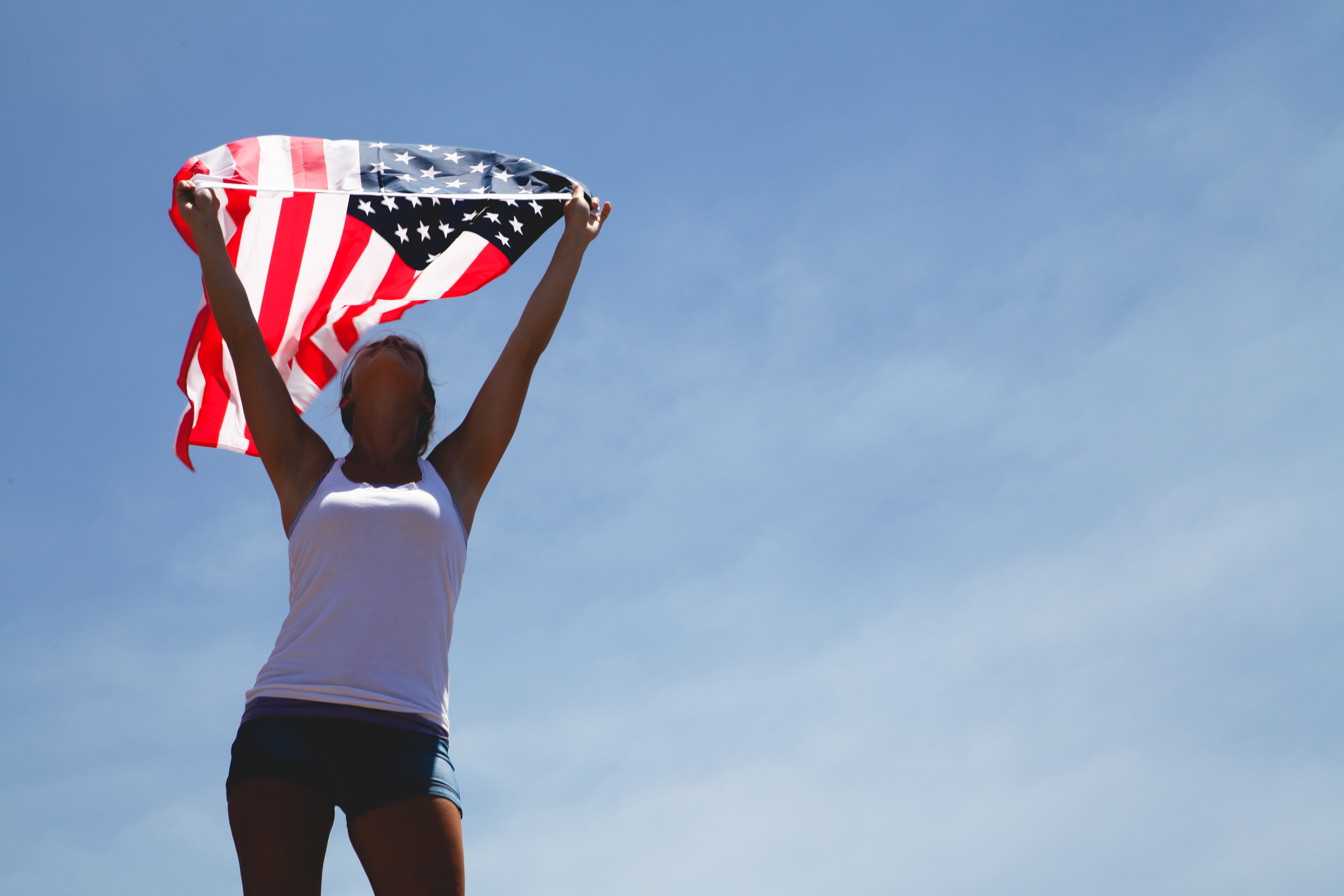 woman in white tank top standing holding u.s.a flag