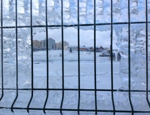 white snowy plains view seen from black steel window grills thumbnail