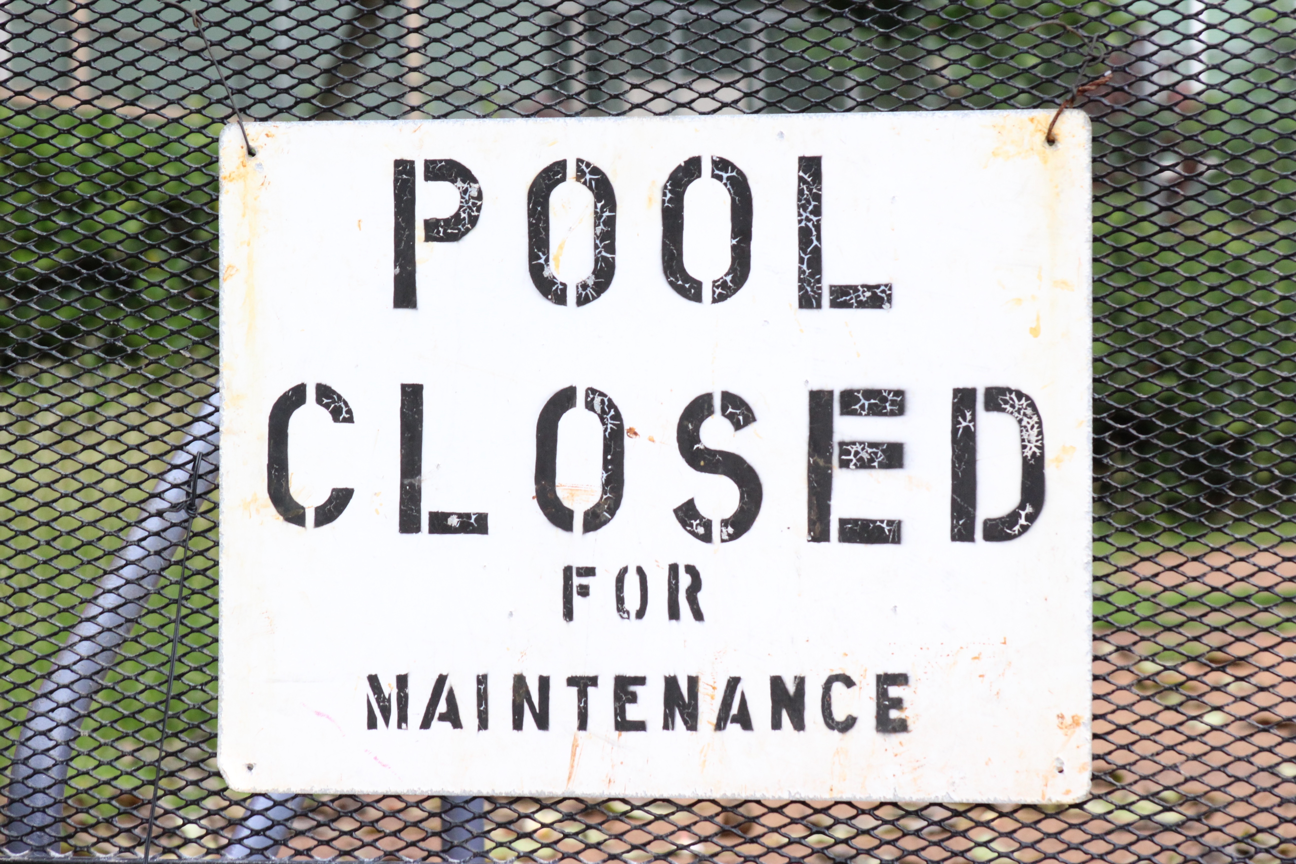 pool closed for maintenance poster hanged on black wired fence