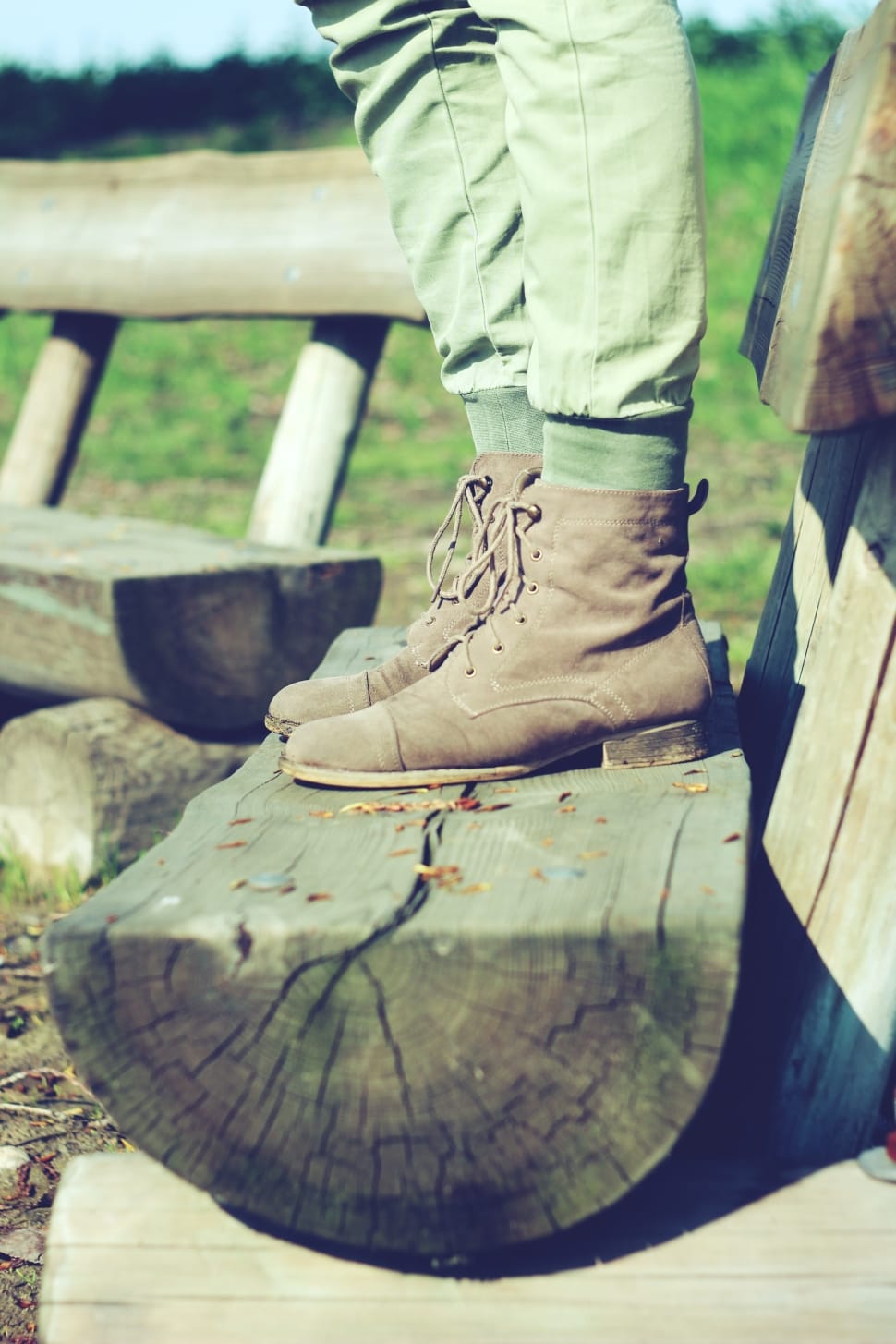 person wearing brown leather lace up boots standing on log preview