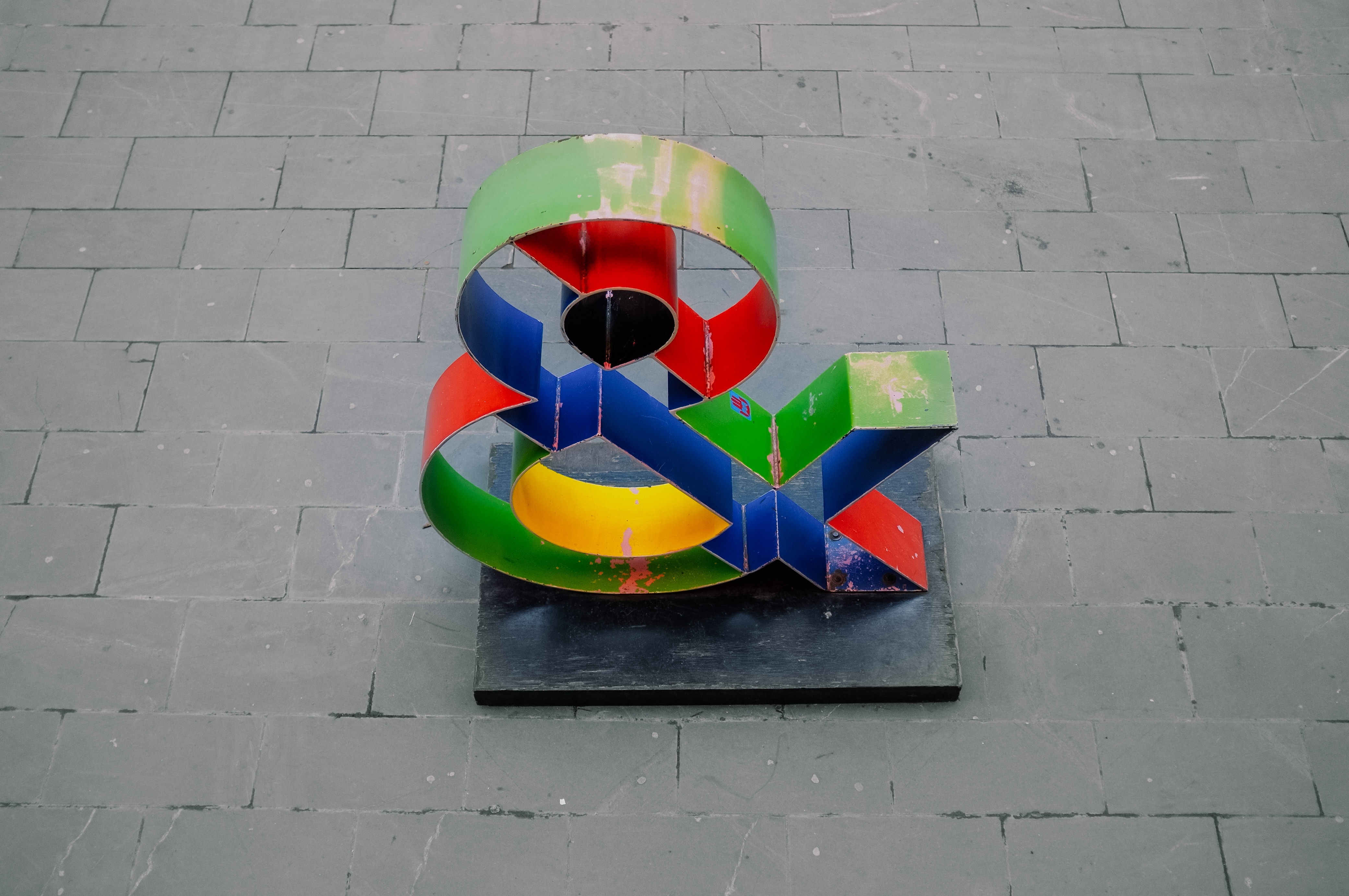 blue, green, and red freestanding ampersand on concrete surface